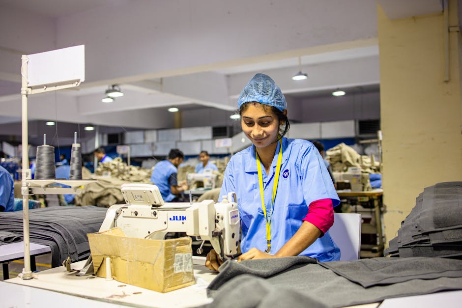 A female textile worker sewing fabric in an industrial factory setting.