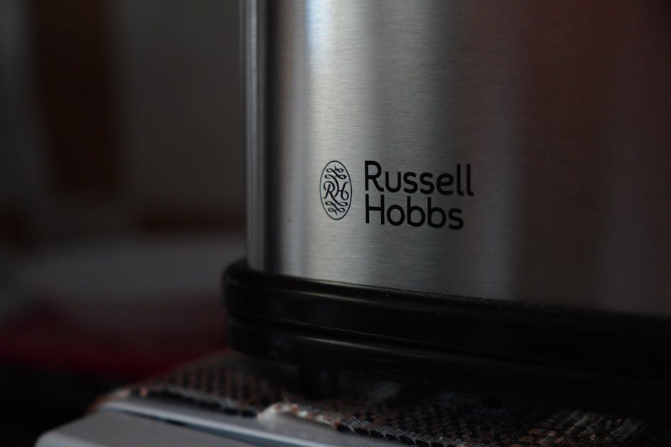 Close-up of the Russell Hobbs logo on a silver appliance with a dark surface in the background.